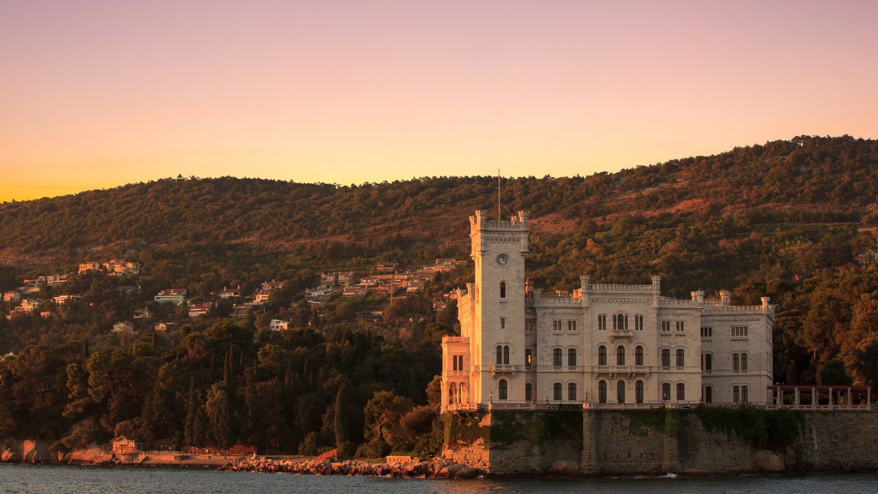 Il maestoso Castello di Miramare si staglia elegante sul mare al tramonto, avvolto da una luce dorata che esalta la sua bellezza senza tempo. Un simbolo iconico di Trieste, incorniciato dal verde del promontorio e dalla quiete dell’Adriatico.