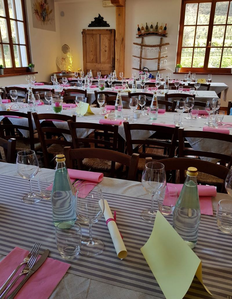 Una sala imbandita all’Osteria Solder: lunghe tavolate con tovaglie a righe, calici brillanti e dettagli colorati in rosa e giallo. Un’atmosfera festosa e curata, ideale per celebrare momenti di convivialità e condivisione.